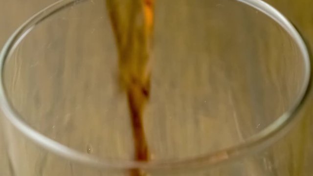 Macro closeup of glass cup as it fills up with splashing blackcurrant berry drink, slow motion 30p