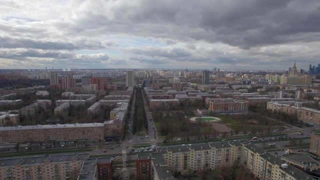 Aerial shot of Moscow. Panoramic city view with apartment blocks, park and car traffic on the roads. Moscow State University in the distance
