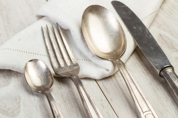 Cuchillo, tenedor y cucharas de metal plata sobre una mesa blanca junto a una servilleta. Vista superior y de cerca. Concepto: Utensilios de cocina. 
