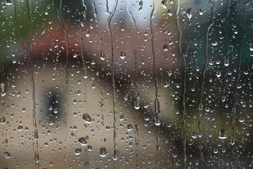 Rain drops on window with house and church in background