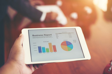 Business person hand holding financial statistics displayed on t