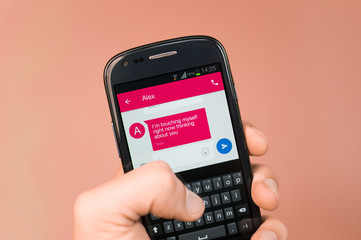 Sexting - modern flirting trough mobile phone. Caucasian hand  writes / reads text message with...