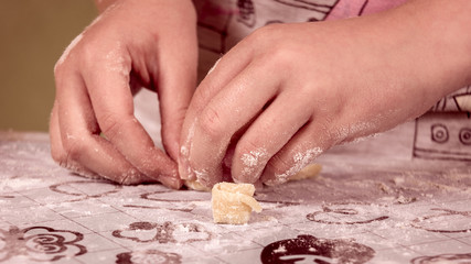 female hands in flour kneading dough on table