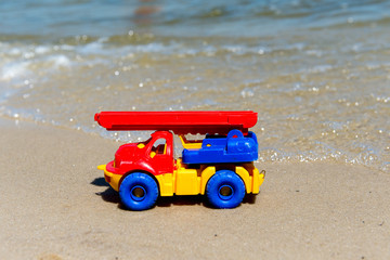 Toy truck with a boom in the wet sand. Summer holidays at sea. Special miniature.