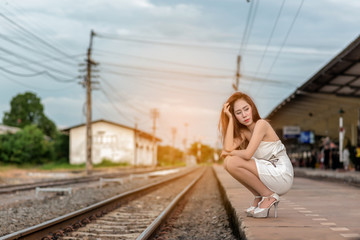 Photos of young travelers at the train station .She boring about she must waiting long time for the train come.