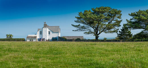 Scenic farmhouse with two trees in a rural area near Saint Issey in north Cornwall.