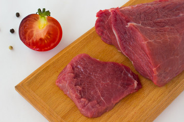 Sliced beef on a cutting board. Tomato and pepper