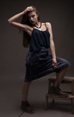 Fototapeta premium sexy fashion model with natural brunette hair, long legs, full lips, perfect skin, wearing brown shoes and long jeans skirt, sitting on floor, beauty photoshoot. Woman with creative make.