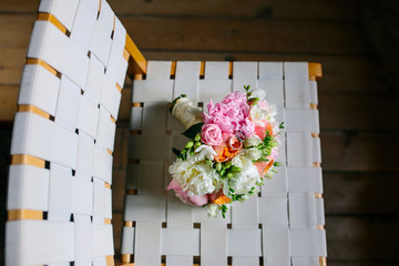 Beautiful wedding bouquet on wooden chair on light background