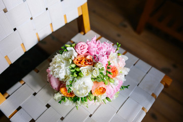 Bouquet of beautiful pink, white and orange peonies on a white chair. Beautiful wedding bouquet.