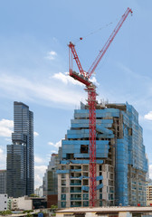 Fototapeta na wymiar Construction / View of building with crane on blue sky background. Focus on building.