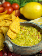 Guacamole in home crafted bowl with tortilla chips around.