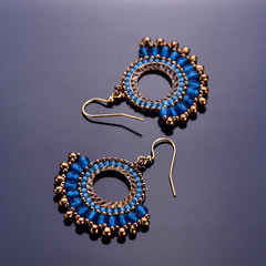 Beaded earrings blue on a dark background. Beadwork. Top view.