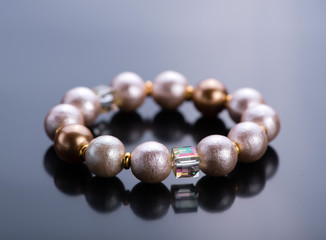 Pearl bracelet with crystals on a dark background. Beadwork.