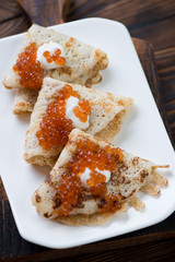 Closeup of crepes served with salmon caviar and sour cream