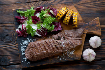 Grilled machete steak with corn and salad, rustic wooden setting