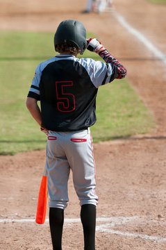 Baseball boy grabbing helmet at home plate