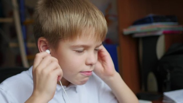 the child listens to music on smartphone in the headphones and hops head in home