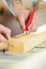 Fototapeta na wymiar Carpenter measures the length of a wood plank before sawing