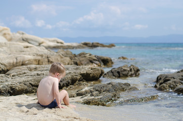 baby boy sitting on sand beach