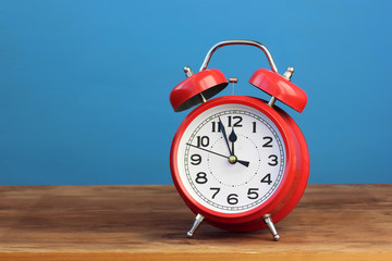 Red retro alarm clock at twelve o'clock.