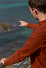 Young man pointing to the sea