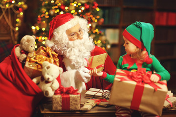 Fototapeta na wymiar Santa Claus and a elf child in a Christmas working, reading lett