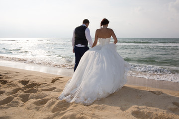 Fototapeta na wymiar Just-married couple standing by the ocean