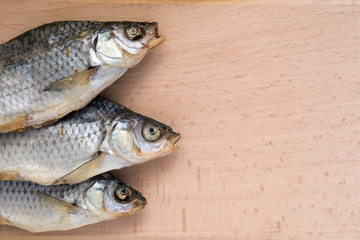 three dried salt fish on a cutting board.