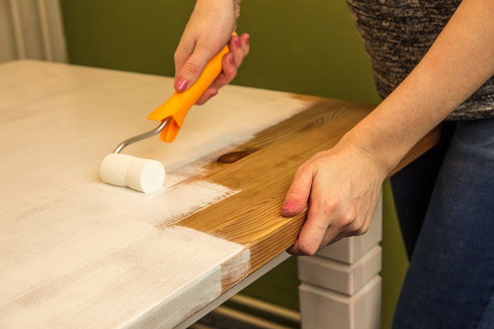 Ein Holztisch wird mit weißer Farbe lackiert