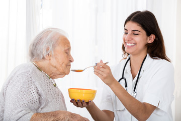 Female Doctor Feeding Soup To Senior Patient