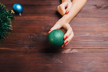 Green Christmas ball in a female hand with red nail polish