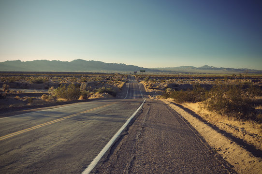 long old asphalt road Route 66 through desert and blue sky