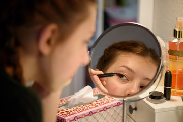 junge Frau beim Schminken vor Spiegel