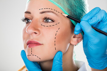 Surgeon Drawing Perforation Lines On Woman's Face