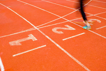 The legs of the woman came jogging on a running track to finish line.