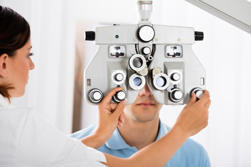 Female Optometrist Adjusting Phoropter For Patient