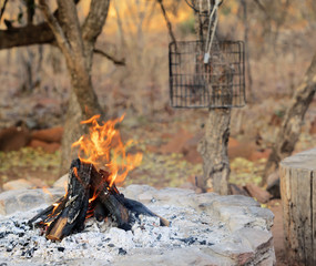 Open wooden campfire in Africa with barbeque grid at the back