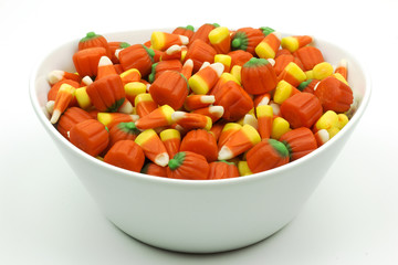 Bowl of candy corn and pumpkins isolated