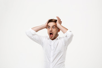 Young successful businessman shouting, panic over white background.