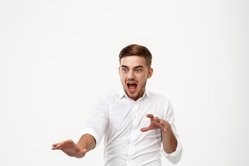 Young successful businessman shouting, panic over white background.