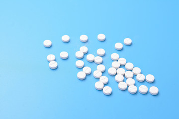 Many pills isolated on light blue background. Pharmaceutical medicament.