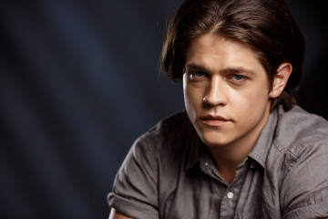 Fototapeta premium Calm young handsome man looking at camera over black background.