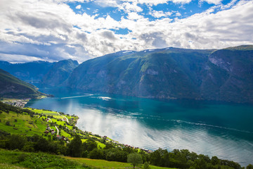 Naklejka na ściany i meble View to Sognefjord in Norway. Small town and cruise port Olden in Norwegian fjords. Bird view of fjord in Norway. under a sunny, blue sky, with the typical rorbu houses. View from the top