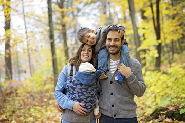 Fototapeta premium Family of four enjoying golden leaves in autumn park