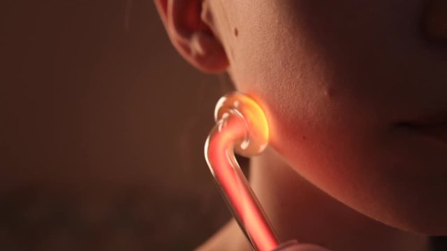 Close up of darsonvalization face of a girl with clay mask in beauty saloon