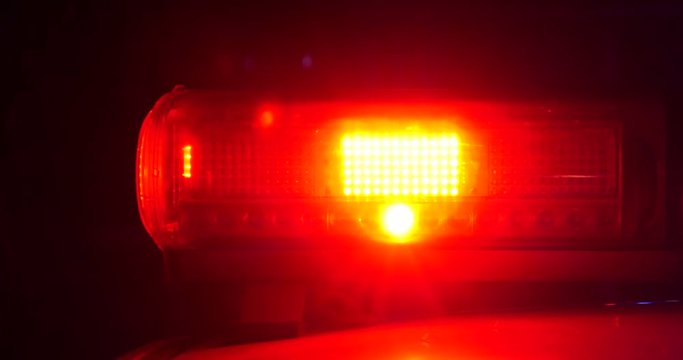 Police lights flashing and passing by cars on street
