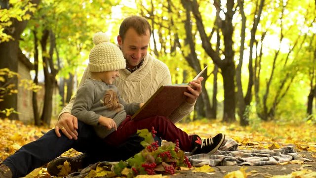 Father and son reading book in yellow autumn park