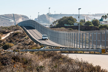 San Diego, California and Tijuana, Mexico international border wall with border patrol vehicle. 