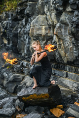 Girl in a black suit with flaming torches .